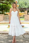 Woman in a white dress standing outdoors with a fountain in the background
