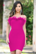 Woman wearing a bright pink dress with feather details outdoors.