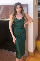 Woman wearing a green satin dress standing indoors.