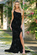 Woman wearing a black sequin dress with a slit outdoors.